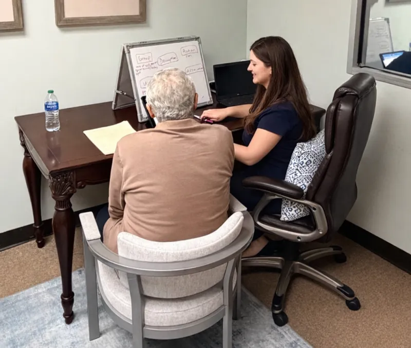 Speech therapist working with an adult patient at a desk during a therapy session