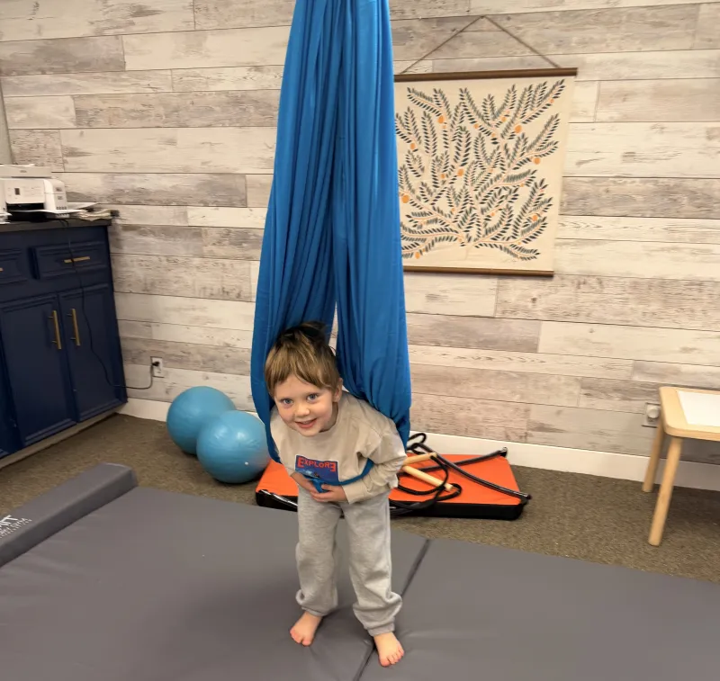 Smiling child enjoying the therapy swing in our Galveston sensory gym